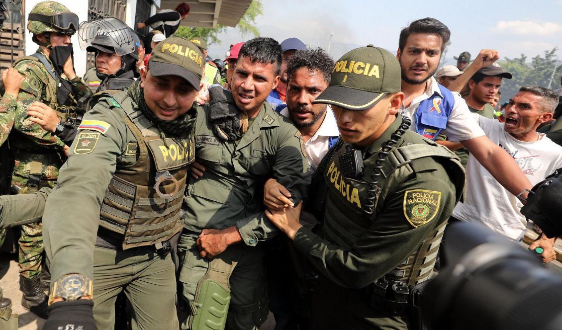 En avhoppad venezuelansk soldat eskorteras av colombianska poliser efter att ha passerat gränsen till Colombia. Foto: Fernando Vergara/AP/TT