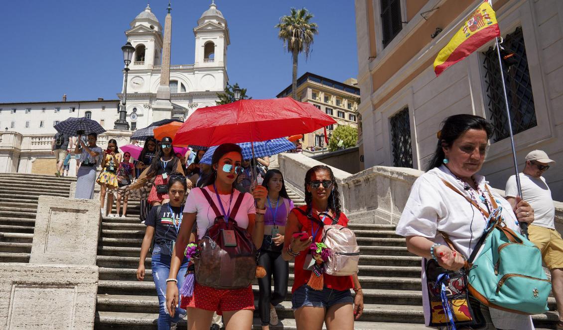 Turister skuggar sig med paraplyer när de går nerför Spanska trappan i Rom på tisdagen. Foto: Andrew Medichini/AP/TT