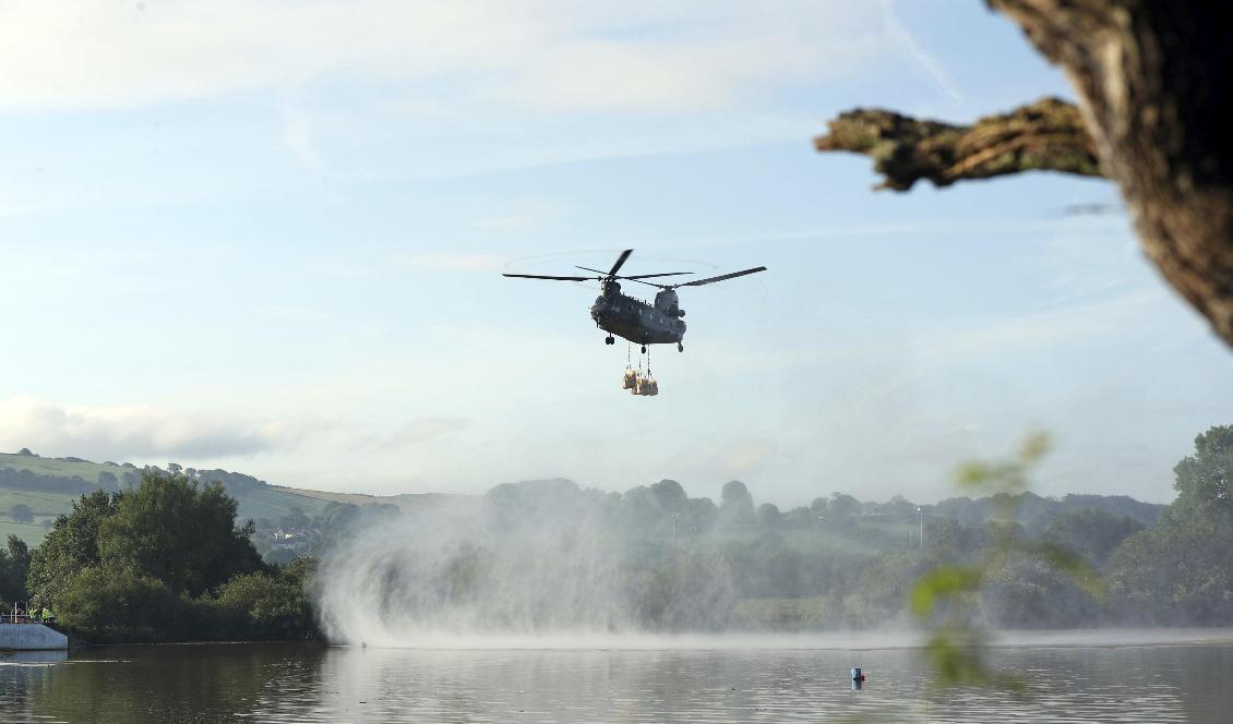 Helikoptern laddad med sandsäckar flyger vattenmagasinet Toddbrook som riskerar att brista. Foto: Yui Mok/TT