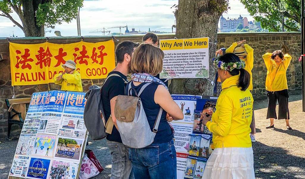 


År efter år finns några Falun Gong-utövare på plats vid Stockholms stadshus för att öva och informera turister. Stockholm den 25 juni 2019. Foto: He Ping/Minghui.org                                                                                                                                                