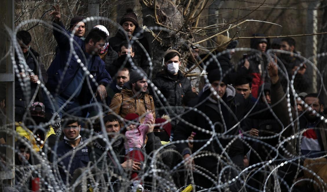 Migranter bakom en avspärrning nära den grekisk-turkiska gränsen i Kastanies. Foto: Giannis Papanikos/AP/TT