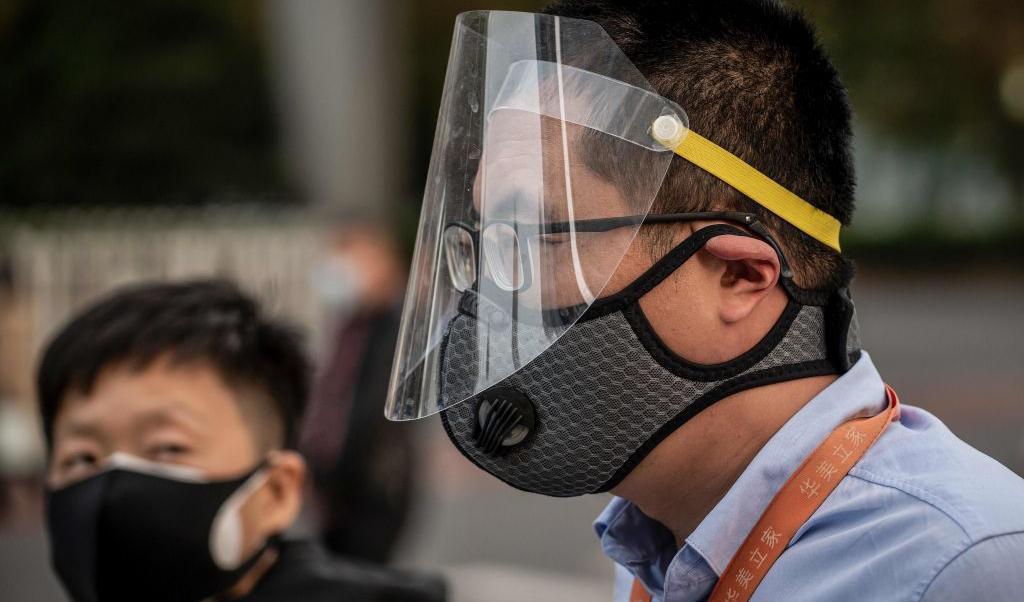 

En man i munskydd och skyddsvisir färdas på en gata i Peking den 7 april 2020. Foto: Nicolas Asfouri/AFP via Getty Images                                                                                                