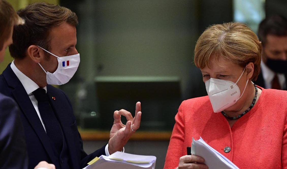 Frankrikes president Emmanuel Macron och Tysklands förbundskansler Angela Merkel studerar ett utkast till coronastöds- och budgetuppgörelse i Bryssel. Foto: John Thys/AP/TT
