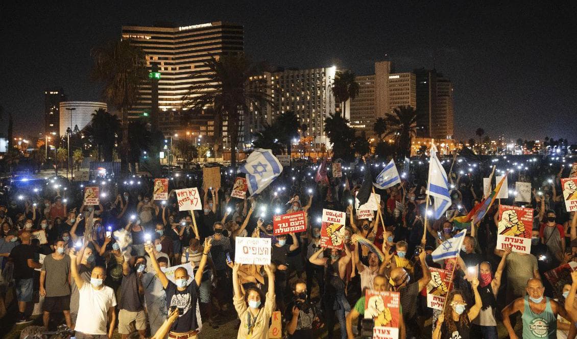 Demonstranter iförda skyddsmasker under lördagens demonstration i Tel Aviv. Foto: Oded Balilty/AP/TT