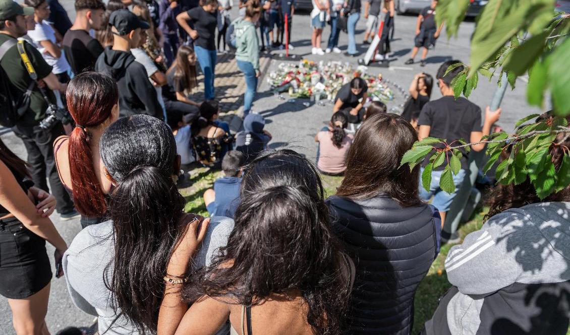 Folk samlas vid blommorna och ljusen på platsen där en tolvårig flicka sköts ihjäl vid en bensinmack i Hallunda i Botkyrka, söder om Stockholm natten mot söndagen. Foto: Stina Stjernkvist/TT