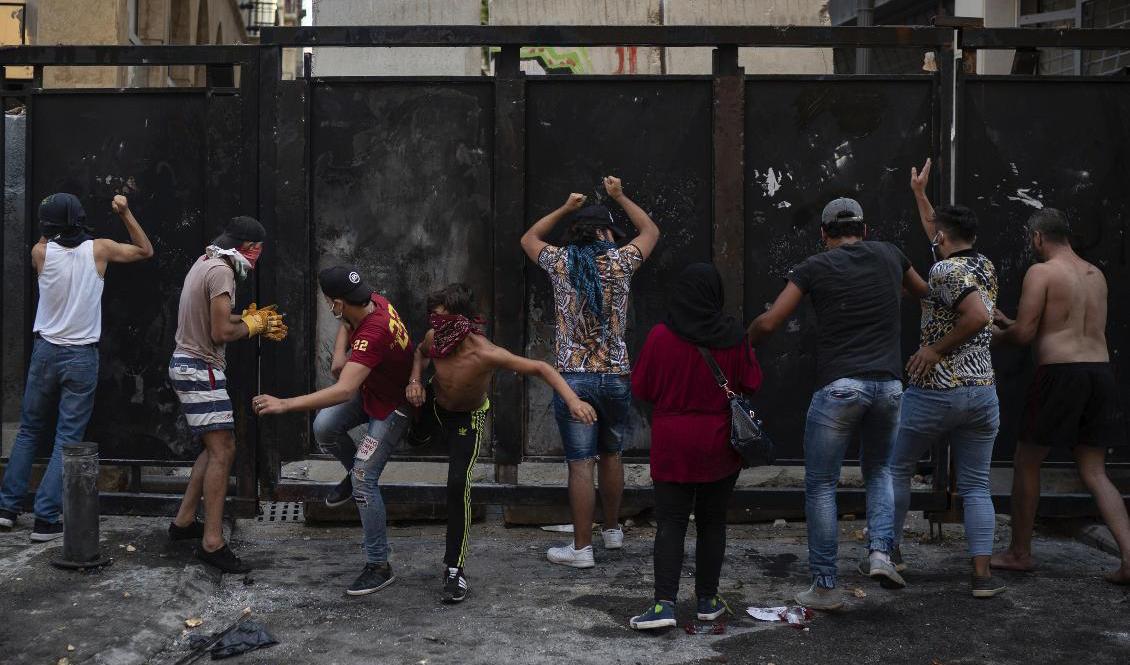 Demonstranter försöker på söndagen ta sig förbi en barriär som rests runt parlamentet i Beirut. Foto: Felipe Dana/AP/TT