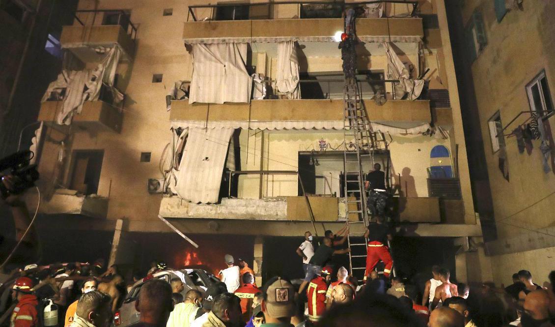 Människor får hjälp att ta sig ut ur sina hem sedan en bränsletank exploderat i Beirut på fredagen. Foto: Bilal Hussein/AP/TT