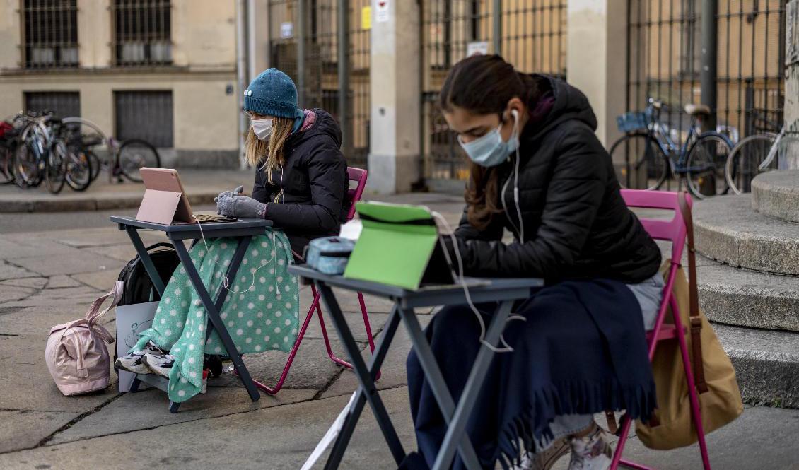 Anita Iacovelli följer distansundervisningen tillsammans med en klasskamrat utanför sin skola i Turin. Arkivbild. Foto: Marco Alpozzi/AP/TT