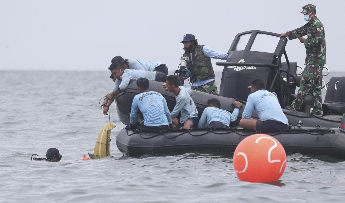 Dykare plockar upp delar från det kraschade flygplanet under söndagen. Foto: Achmad Ibrahim/AP/TT