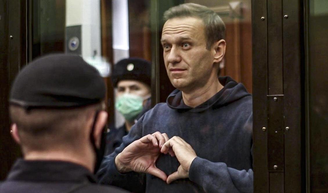 Den ryska oppositionspolitikern Aleksej Navalnyj tecknar ett hjärta mot sin hustru Julia Navalnaja när hans tidigare villkorliga straff i tisdags i en domstol i Moskva omvandlade till ett fängelsestraff. Foto: Moscow City Court/AP/TT