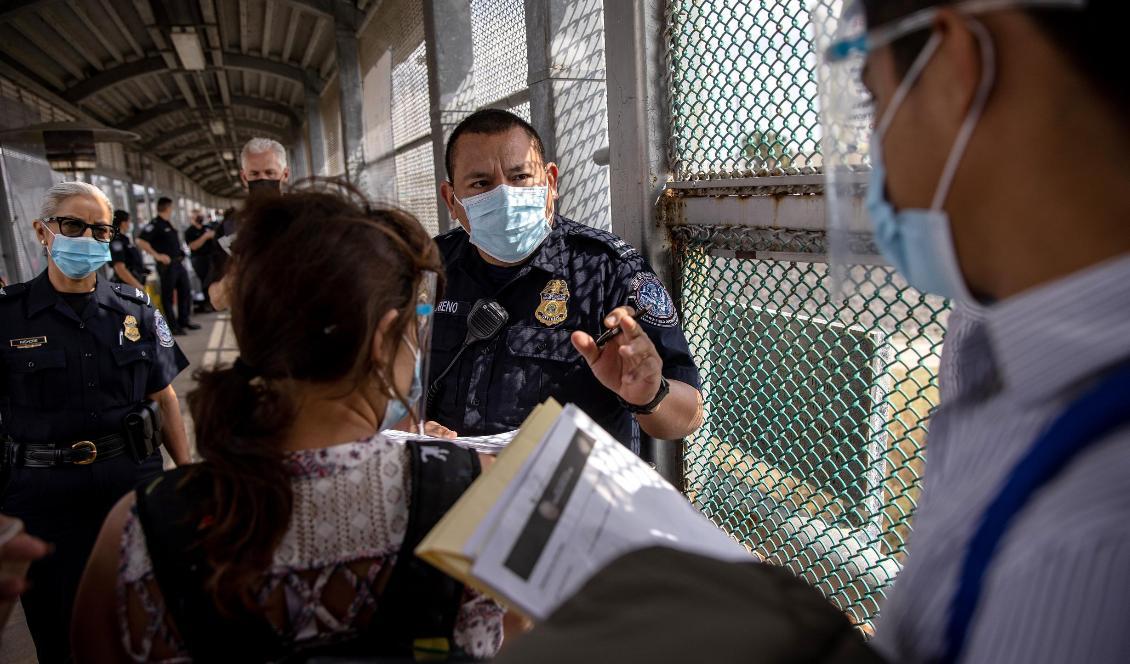
En amerikansk gränspolis pratar med migranter som söker tillstånd att flytta från ett migrantläger in i USA, vid gränsen mellan Mexiko och USA. Foto: John Moore/Getty Images                                            