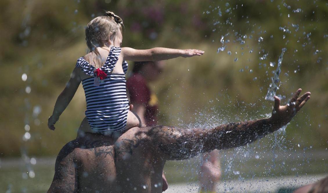 Beau Jess och treåriga dottern River söker svalka i Arlington i den amerikanska delstaten Washington. Foto: Andy Bronson/AP/TT
