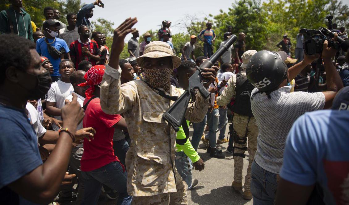Poliser vid en samling människor som protesterar mot mordet på Haitis president. Foto: Joseph Odelyn/AP/TT