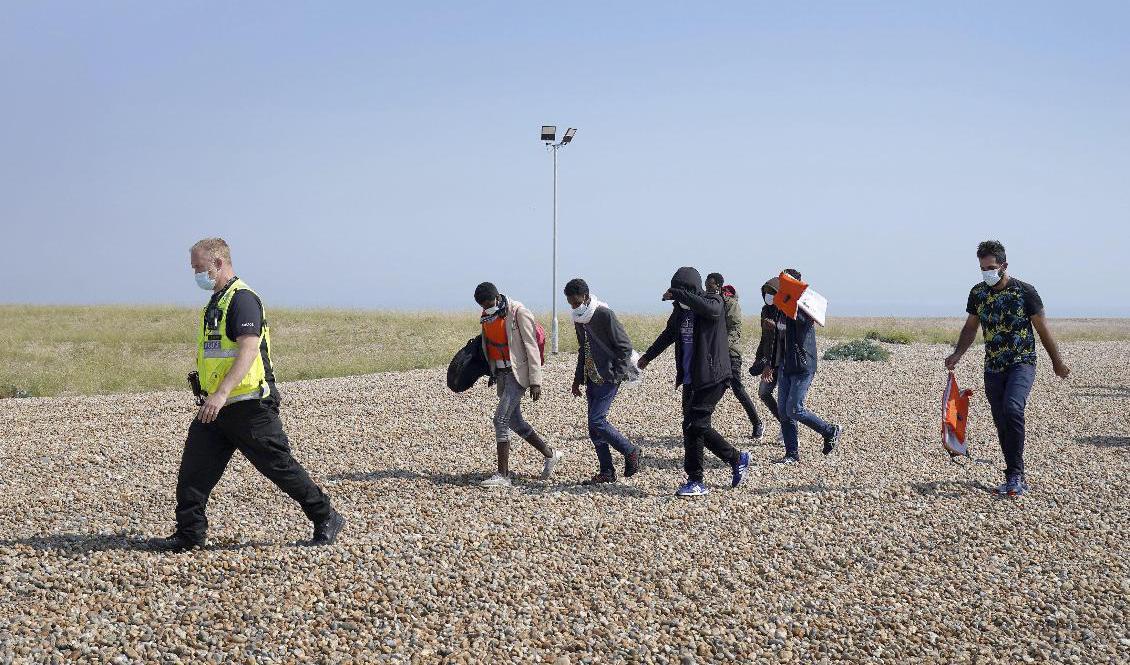 Polis eskorterar en grupp människor som tros ha anlänt sjövägen till Dungeness i södra England. Foto: Gareth Fuller/AP/TT