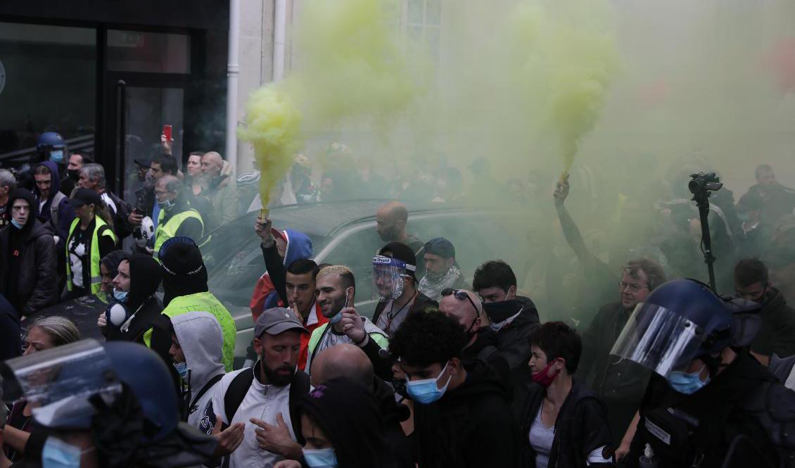 Med rökfacklor protesterar människor i Paris mot covidpasset som från måndag krävs för bland annat kafébesök och tågresor i Frankrike. Foto: Adrienne Surprenant/AP/TT