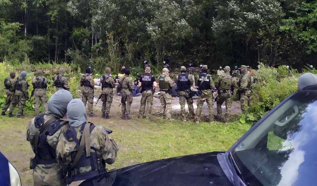 Migranter och polska gränspoliser vid gränsen mot Belarus. Arkivbild. Foto: Mateusz Wodzinski/AP/TT