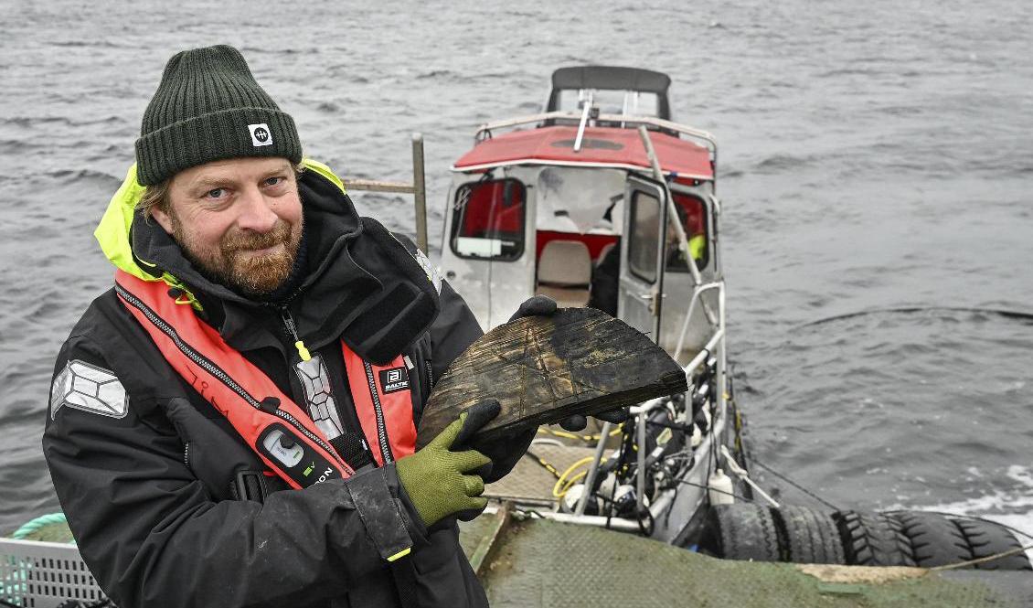 Jim Hansson med en del av ett lock där man kan se ett bomärke. Det kan ge till mer information om vem lasten tillhörde. Foto: Anders Wiklund/TT