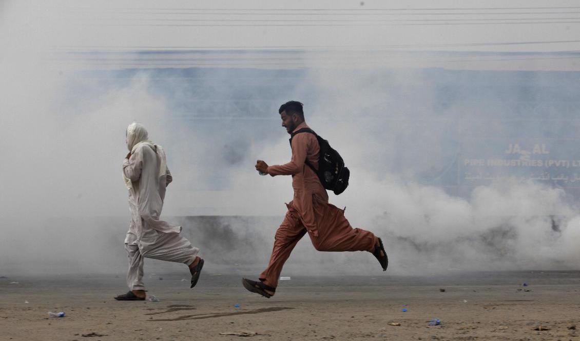
TLP-anhängare tar skydd från polisens tårgas. Foto: K M Chaudary/AP/TT                                            