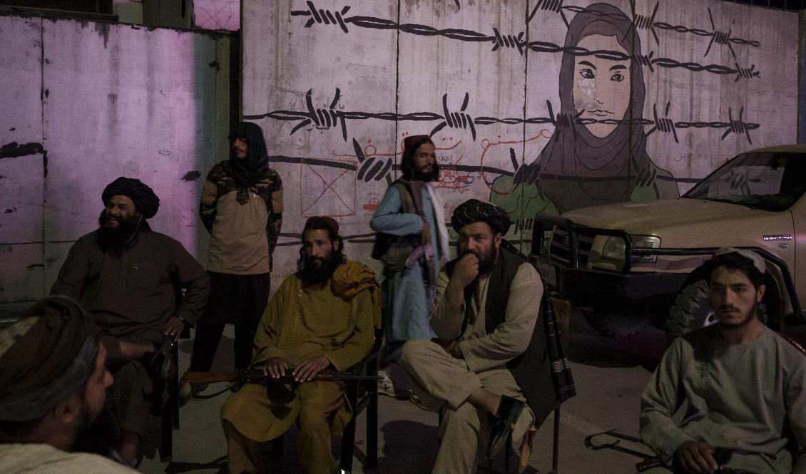 En grupp talibaner i samtal framför en väggmålning i Kabul. Arkivbild. Foto: Felipe Dana/AP/TT