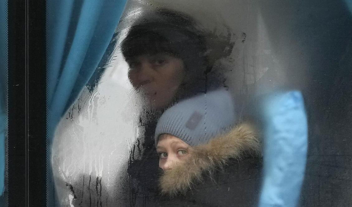 En kvinna och hennes barn på en buss i färd att lämna Luhansk i östra Ukraina, efter Rysslands attack på torsdagen. Foto: Vadim Ghirda/AP/TT
