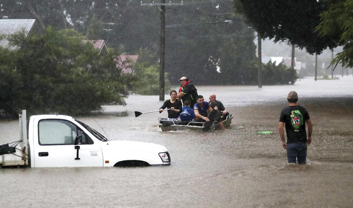 Invånare i staden Lismore på Australiens östkust försöker ta sig genom vattenmassorna under måndagen. Foto: Jason O'Brien/AP/TT