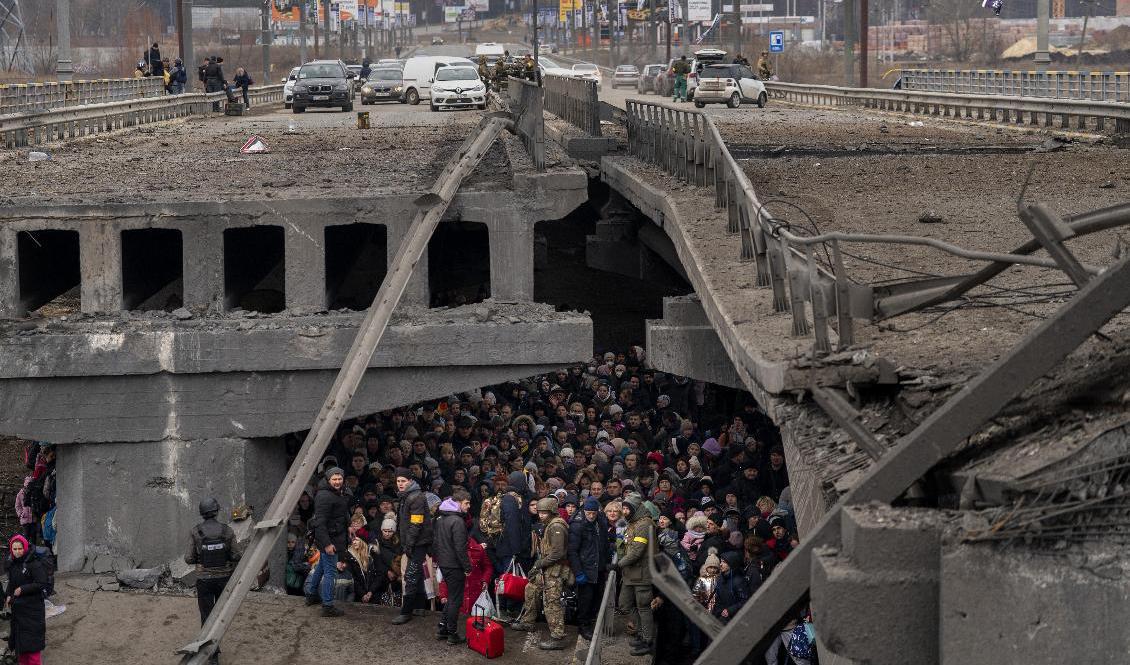Människor tar skydd under en förstörd bro i Kievs utkanter. Foto: Emilio Morenatti/AP/TT