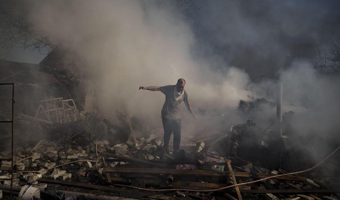 En man går över bråten från ett uppbrunnet hus som förstörts i ett ryskt anfall i Charkiv. Foto: Felipe Dana/AP/TT