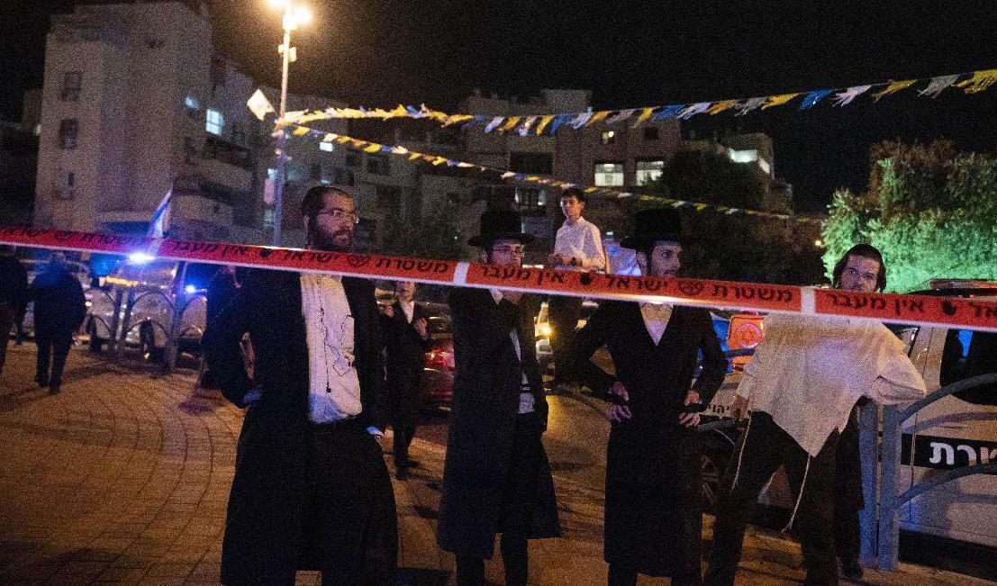 
Ultraortodoxa judar står bakom polisens avspärrningar i Elad i torsdags kväll, då den dödliga attacken ägde rum. Foto: Maya Alleruzzo/AP/TT                                            