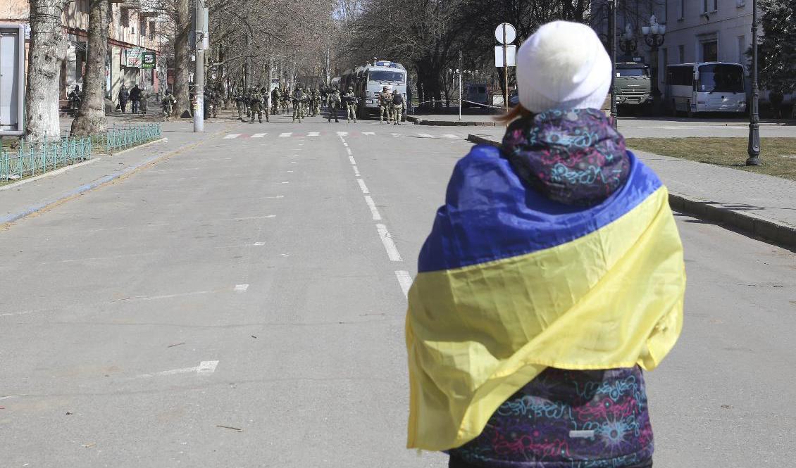 En kvinna i Cherson insvept i en ukrainsk flagga protesterar mot den ryska ockupationsmakten. Bilden är tagen 19 mars. Foto: Olexandr Chornyi/AP/TT
