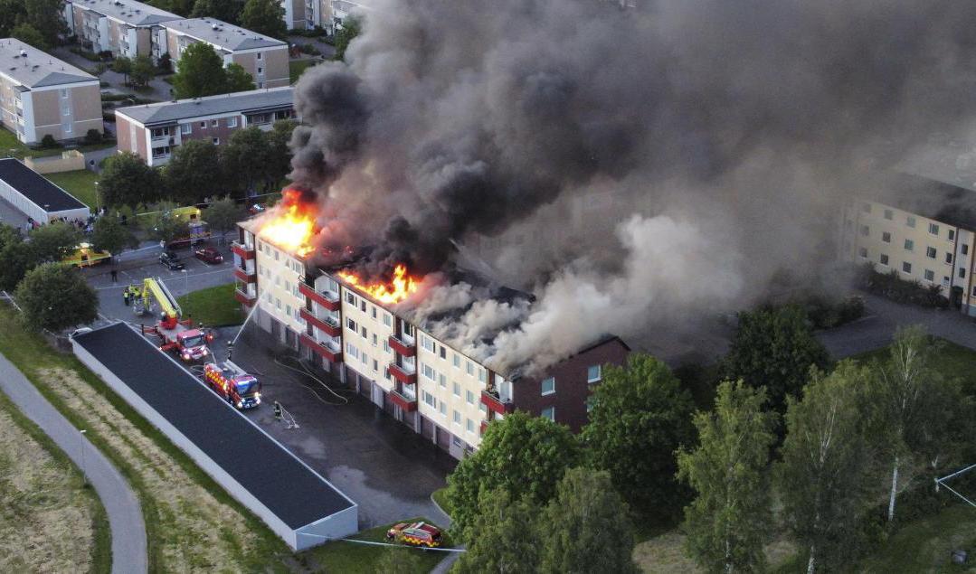 Branden har spridit sig till vinden på flerfamiljshuset. Foto: Christian Svensson/TT