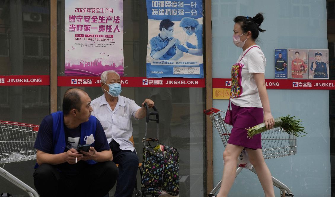 Flera personer vid en affisch för vaccineringar i Peking. Foto: Ng Han Guan/AP/TT