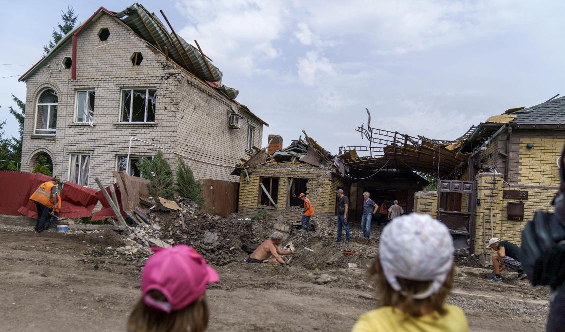 Barn ser på när räddningsmanskap går igenom skadorna efter en granatattack i Kramatorsk i östra Ukraina. Inga personer skadades i attacken i fredags. Foto: David Goldman/AP/TT