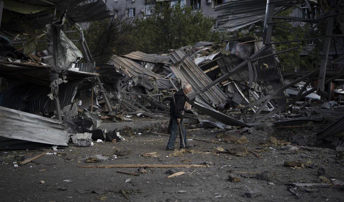 En äldre man går förbi en butik som förstörts i en rysk attack mot Zaporizjzja den 11 oktober. Foto: Leo Correa/AP/TT