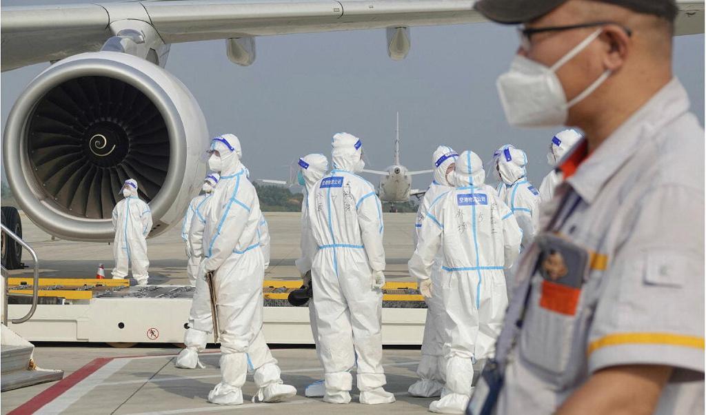 Flygplatsarbetare jobbar i medicinsk skyddsutrustning kring en utrikesflight på Yantai-flygplatsen i Shandongprovinsen i östra Kina. Foto: STR/AFP via Getty Images