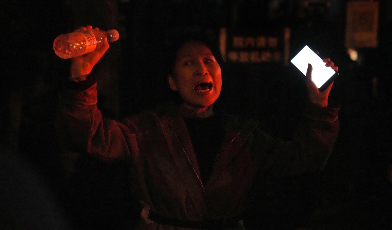 En kvinna protesterar i Peking mot regimens strikta "nollcovid"-politik. Foto: Ng Han Guan/AP/TT