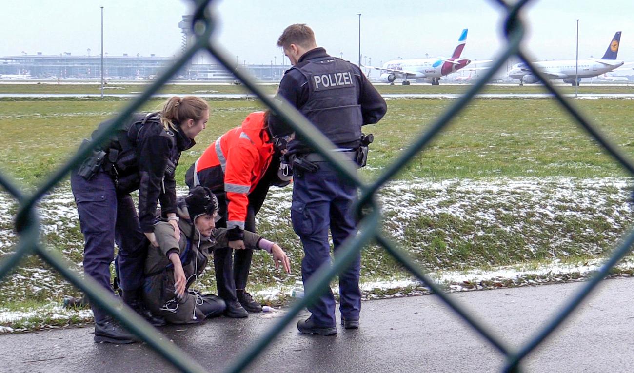 Polis försöker lyfta bort en klimataktivist från gruppen Sista generationen från en väg på Berlin Brandenburgs flygplats den 8 december. Foto: Paul Zinken/AP/TT