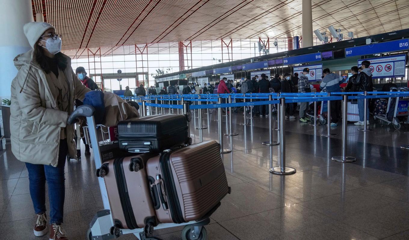 En resenär ska precis checka in på Pekings internationella flygplats under torsdagen. Nu vidtar en rad länder åtgärder för resenärer från Kina med anledning av den ökade smittspridningen i landet. Foto: Andy Wong/AP/TT