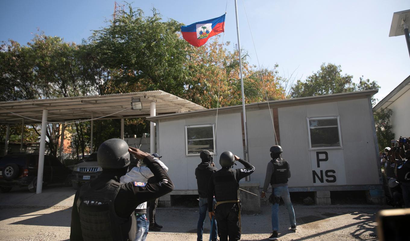 Poliser gör honnör vid Haitis flagga som halats på halv stång i Port-au-Prince. Foto: Odelyn Joseph/AP/TT