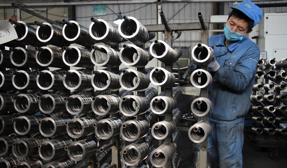 En arbetare placerar aluminiumkolvar för fordonsmotorer på en produktionslinje vid en maskintillverkningsfabrik i Binzhou, i östra Kinas Shandongprovins. Foto: STR/AFP via Getty Images