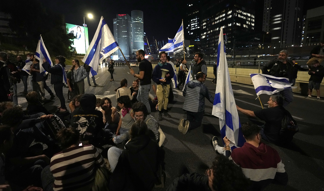 Israeler blockerar en motorväg utanför Tel Aviv i protest mot regeringens förslag att ändra rättsväsendet. Foto: Ohad Zwigenberg/AP/TT