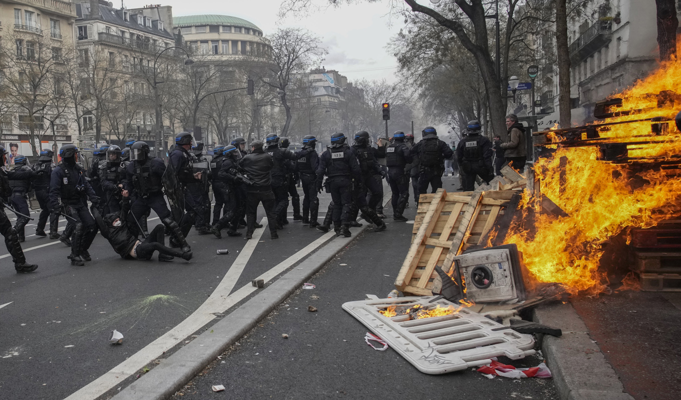 Kravallutrustad polis i sammandrabbning med demonstranter i Paris. Foto: Christophe Ena/AP/TT