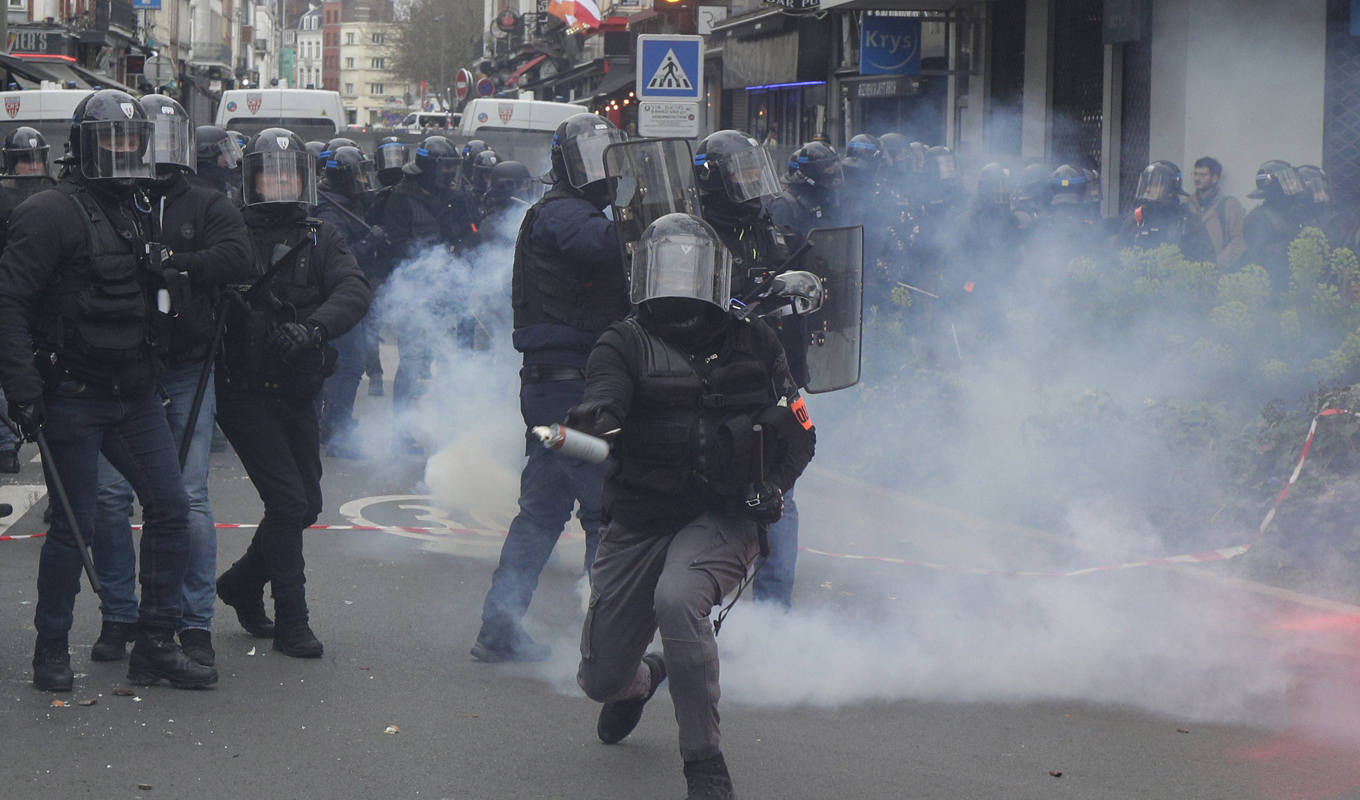 En polis förbereder sig för att kasta en tårgas under demonstrationen i Lille. Foto: Michel Spingler/AP/TT