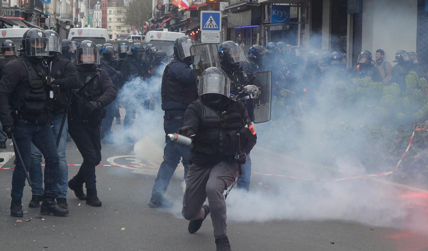En polis förbereder sig för att kasta en tårgas under demonstrationen i Lille. Foto: Michel Spingler/AP/TT