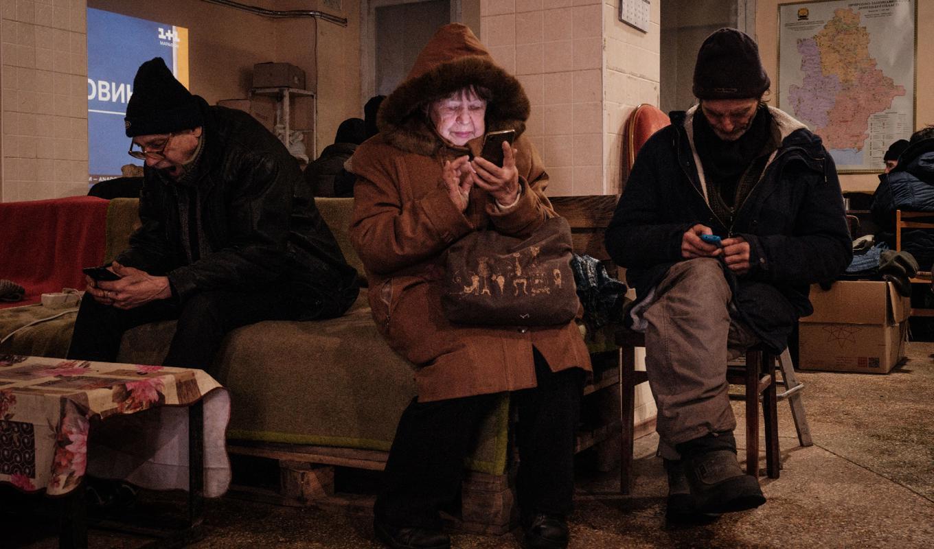 En ukrainsk kvinna använder en smarttelefon vid ett humanitärt centrum, dit hon tagit sig efter krigsutbrottet 2022. Foto: Yasuyoshi Chiba/AFP via Getty Images
