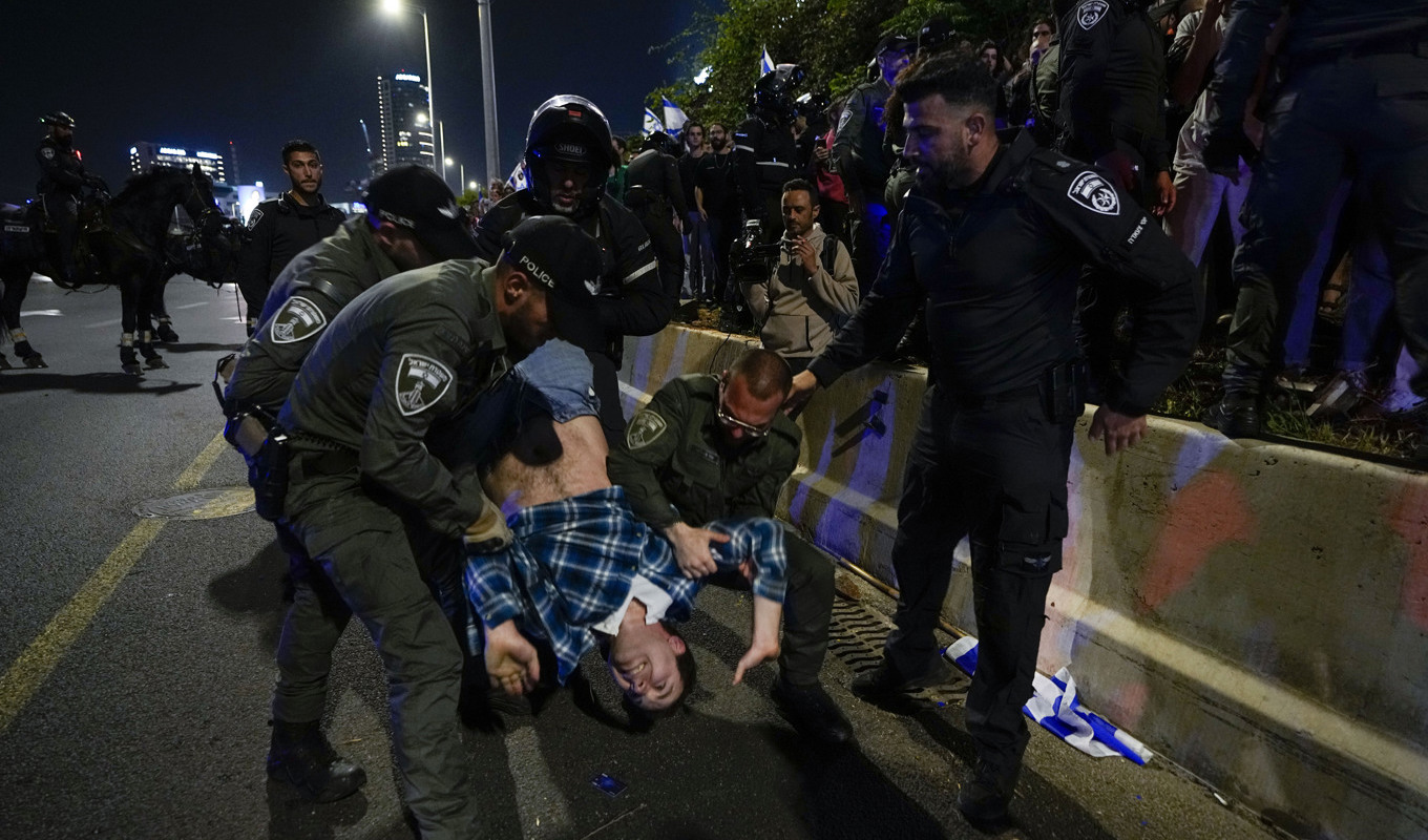 Israelisk polis flyttar på demonstranter som blockerar en motorväg invid Tel Aviv under en protest mot den israeliska regerings planer på att förändra rättsväsendet. Foto: Ariel Schalit/AP/TT