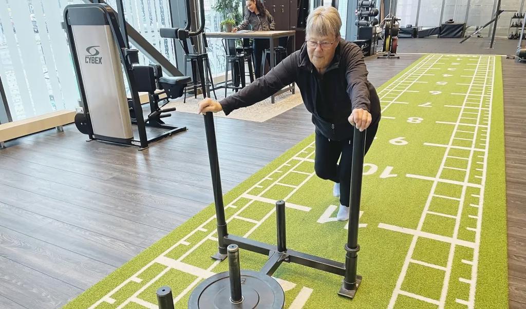 Agneta Spångberg, 75 år, visar på ett riktigt kraftprov genom att skjuta en metallsläde lastad med en viktplatta framför sig.Foto: Göran Jacobsson