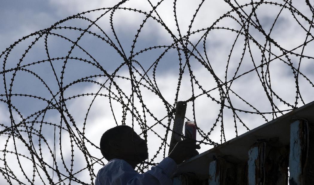 En mexikansk migrant hänger träkors på ett gränsstängsel mellan USA och Mexiko. En del migranter dör i sina försök att komma till USA. Foto: Guillermo Arias/AFP via Getty Images