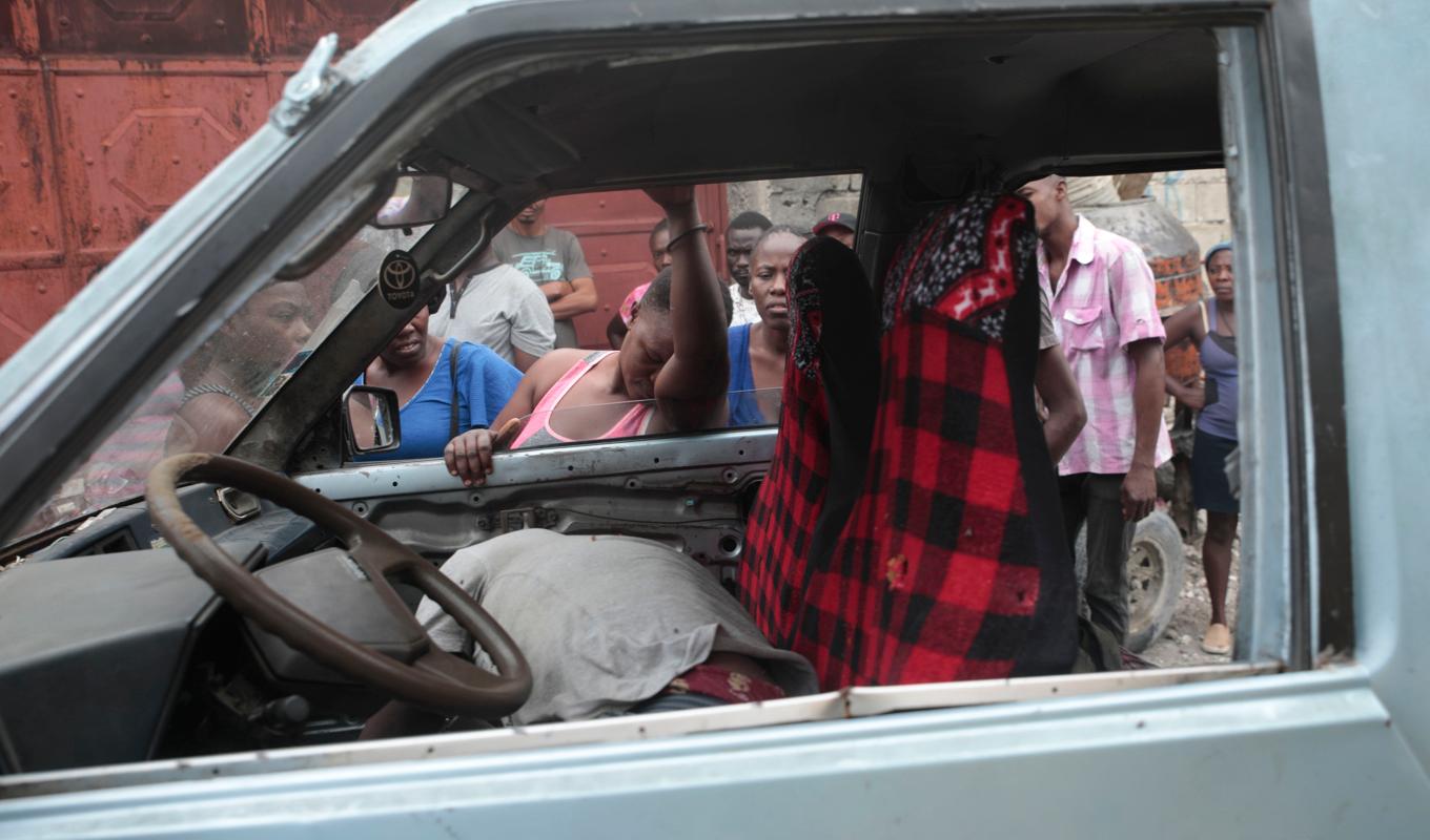 Förbipasserande tittar på en man som dödats av okända gärningsmän i Haitis huvudstad Port-au-Prince den 25 april. Foto: Odelyn Joseph/AP/TT