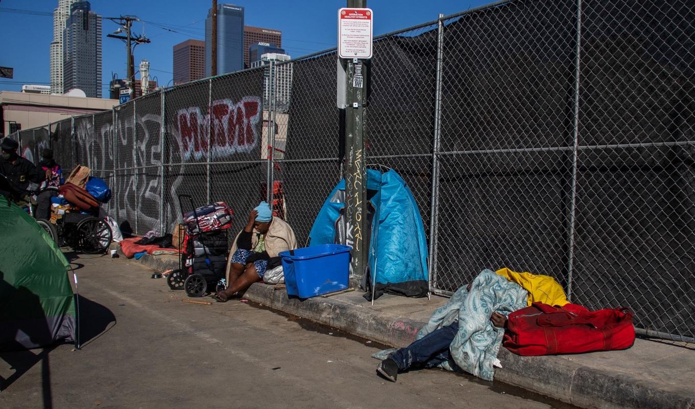 Hemlösa sitter och sover på en trottoar i Los Angeles i USA den 25 november 2021. Antalet hemlösa i Kalifornien fortsätter att öka, trots att delstaten avsätter miljardtals dollar årligen för att få bukt med problemet. Foto: Apu Gomes/AFP via Getty Images