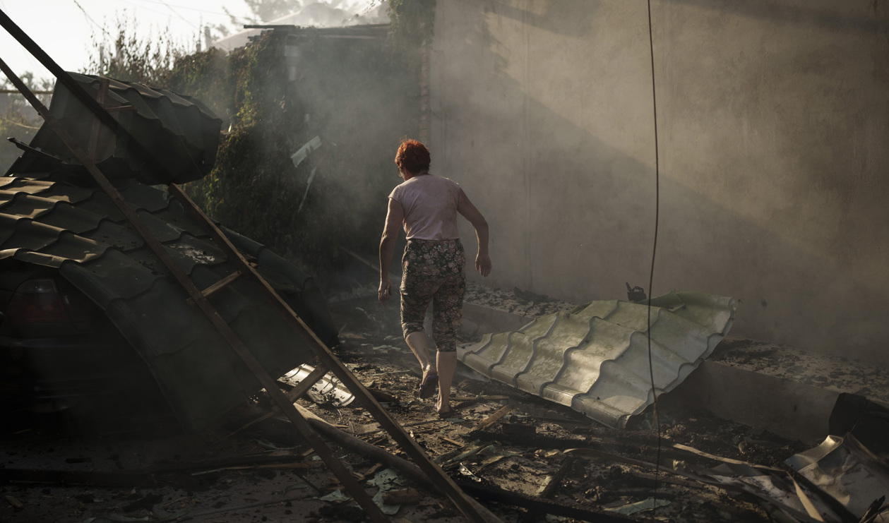 En kvinna utanför sitt sönderbombade hus tidigare i sommar i Cherson. Foto: Felipe Dana/AP/TT